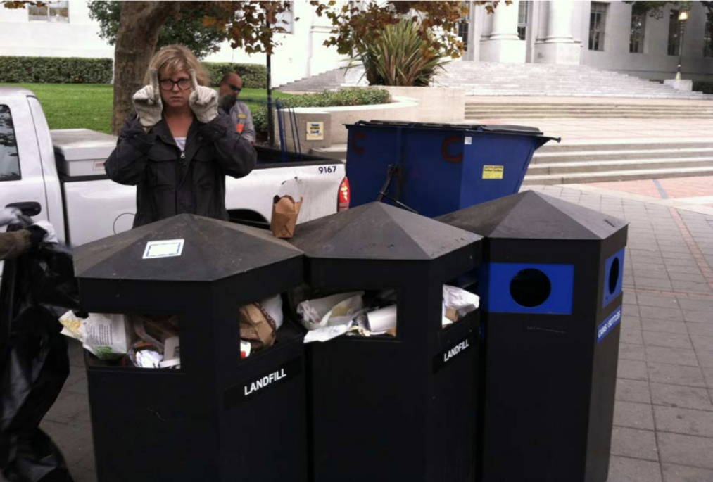 Person standing behind three trash bins