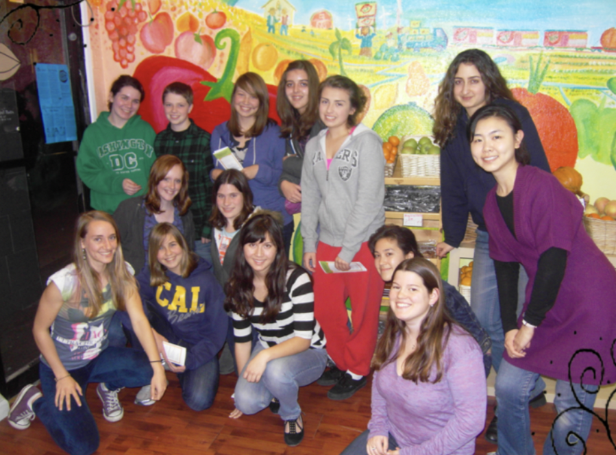 14 people standing in front a mural of a farm